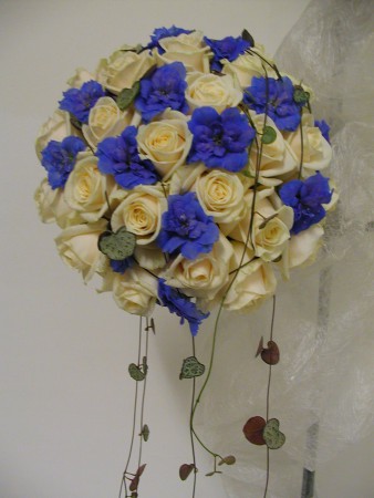 Rund i hållare med vendelarosor och blå delfinumblommor 